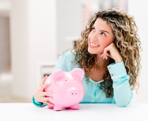 Thoughtful woman with a piggybank looking very happy